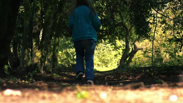 Woman running through woodland in dappled summer sunshine