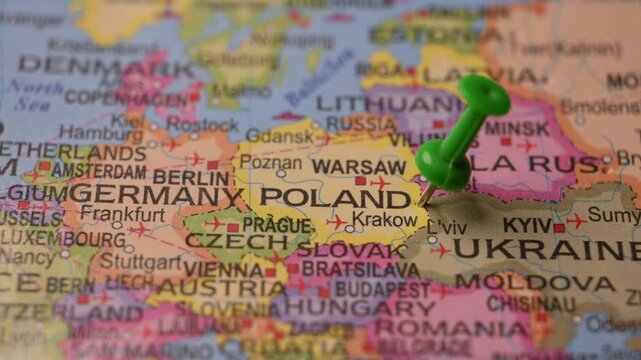 Close-Up World Map Shot Featuring Green Pin Highlighting Poland Pointed by Hand