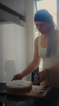 Mother undergoing chemotherapy cutting cake in kitchen at home, headscarf cancer patient preparing dessert, daily life activity, recovery routine, resilience, normalcy and independence