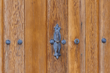 Antique iron door handle and decorative studs on light wood door