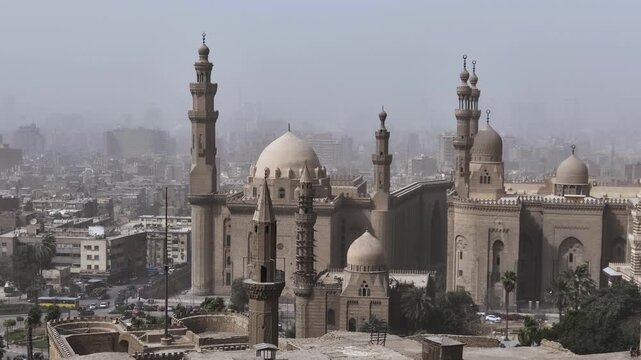 Historic mosques with tall minarets and grand domes dominate the hazy Cairo cityscape, Egypt, showcasing stunning Mamluk Islamic architecture from the medieval period.
