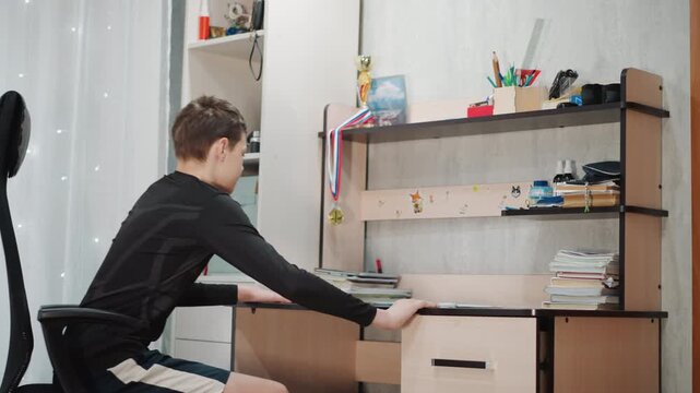 Young boy focused on academic activities indoors. Teenager concentrating deeply on schoolwork inside cozy space. Young male student dedicating time to studies in comfortable and quiet indoor setting