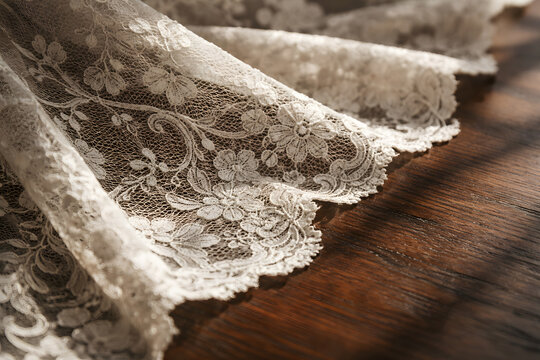 Intricate vintage lace fabric resting on dark wood