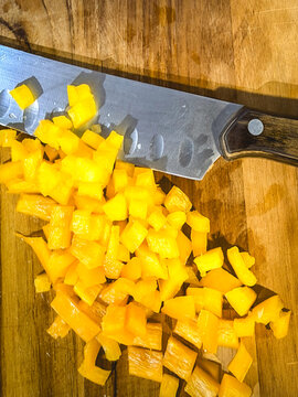 Cubes yellow peppers, on a wooden cutboard.