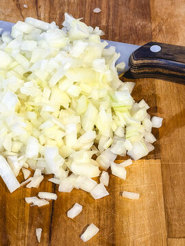 Cubes of onion, on a wooden cutboard.