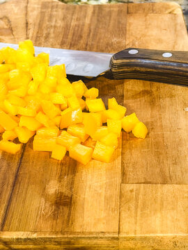 Cubes yellow peppers, on a wooden cutboard.
