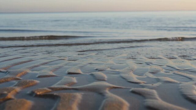 Tranquil Seascape with Gentle Waves Washing Ashore on Textured Sand During Golden Hour, Symbolizing