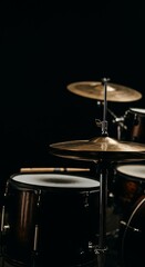 Obraz premium Drums on Stage With Cymbals and Wood Sticks Ready for a Live Performance in a Dark Setting