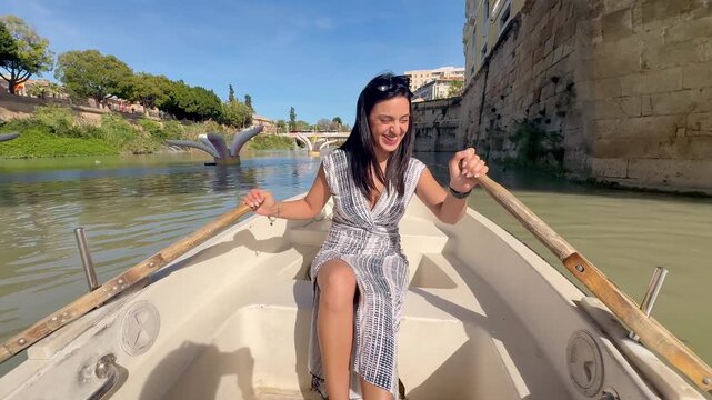 Latin woman paddling canoe on Segura River in Murcia, Spain, smiling and enjoying summer afternoon, travel lifestyle and freedom concept