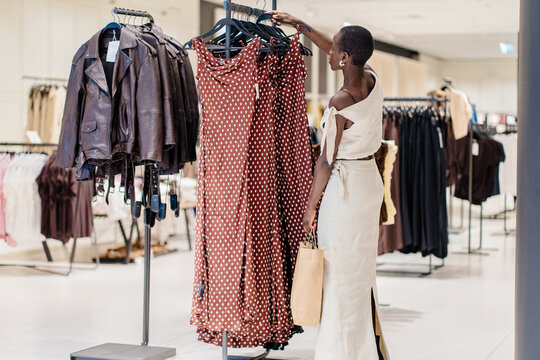 African American Woman Inspecting Polka Dot Dress in Fashion Store