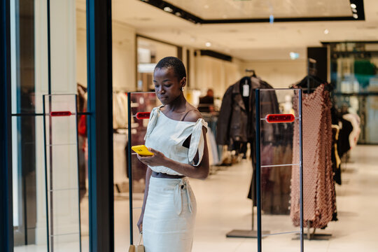 Black Woman Checking Smartphone While Shopping in Apparel Store