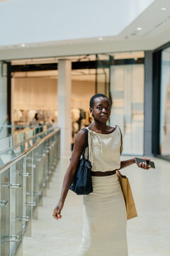 Elegant African American Woman Walking in Modern Shopping Mall with Bags