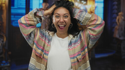 Woman hands on head laughing with mouth open in museum building, wearing glasses, hoop earrings and patterned shirt  joy discovery. © Krakenimages.com
