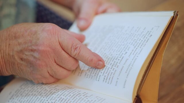 Closeup elderly hand tracing braille. Nostalgic scene of grandmother sharing tactile story, slow fingertips exploring raised dots, warm home light, quiet reflection, emotional connection with grandson