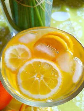 Lemon slices in orange juice with ice cubes in the glass fresh citrus fruit summer background