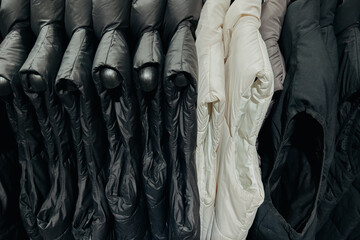 Diverse puffer jackets hanging on metal clothing rail in store © reddish