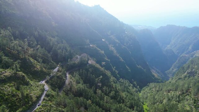 Aerial view of Curral das Freiras, Madeira, nestled in a deep valley surrounded by verdant mountains. A modern tourist complex is visible.