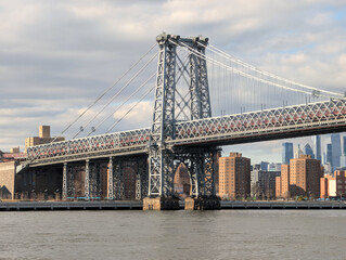 Obraz premium Stunning Manhattan Bridge spanning the East River with New York City skyline, towering skyscrapers, and vibrant urban architecture under dramatic daylight sky, travel Usa