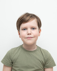 Fototapeta premium An emotional boy stands in a green T-shirt on a white background