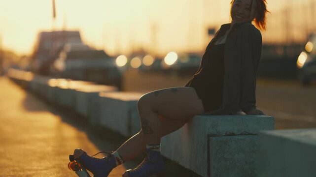 Tattooed woman sitting with roller skates at sunset