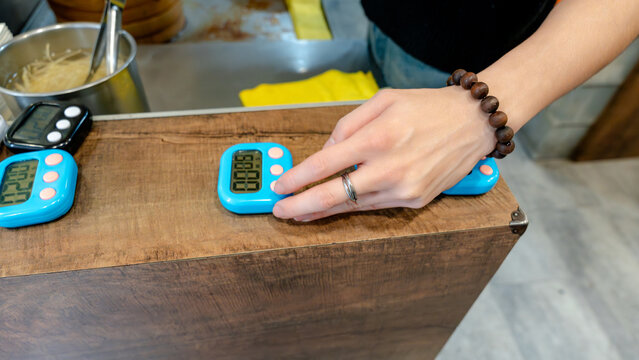 Restaurant worker sets digital timer in kitchen