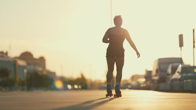 Woman roller skating on an urban street at sunset