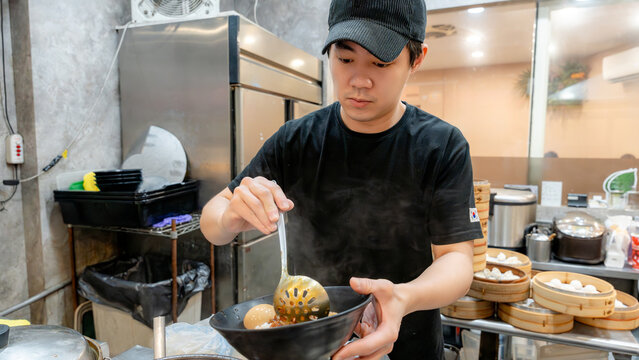 Taiwanese chef serving traditional dish in the kitchen