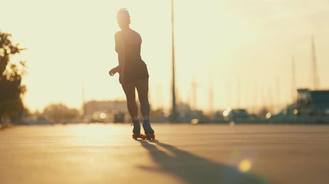 Silhouette of a woman roller skating at sunset