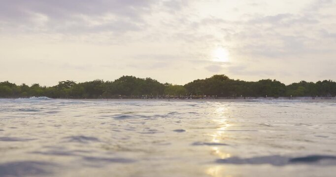 Ocean with waves and the shoreline with sunset sky