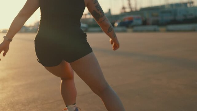 Tattooed woman roller skating down an empty street at sunset