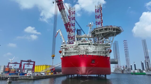 Rotterdam, Netherlands. Drone flight over industrial area with cargo ports, containers and a semi-submersible ship, heavy lifting crane. Machines designed for work at sea