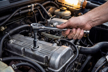 Fototapeta premium Mechanic Hand Using Ratchet Wrench on Car Engine for Repair