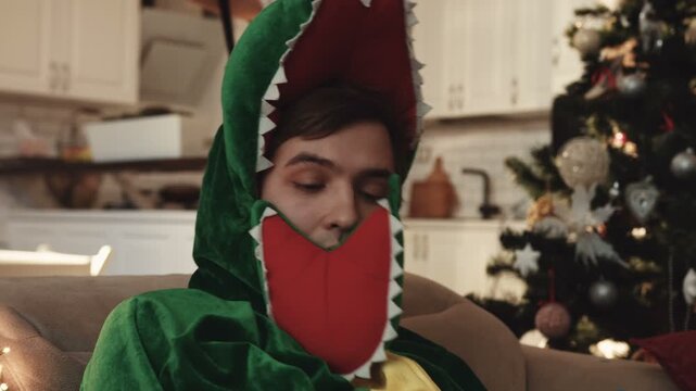 Nice guy in dinosaur costume waking up in unfamiliar apartment after New Year&rsquo;s Eve party. Surprised guy seeing missed call on mobile phone screen