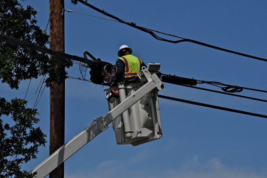 Linesman working on fiber optic lines using cherry picker 