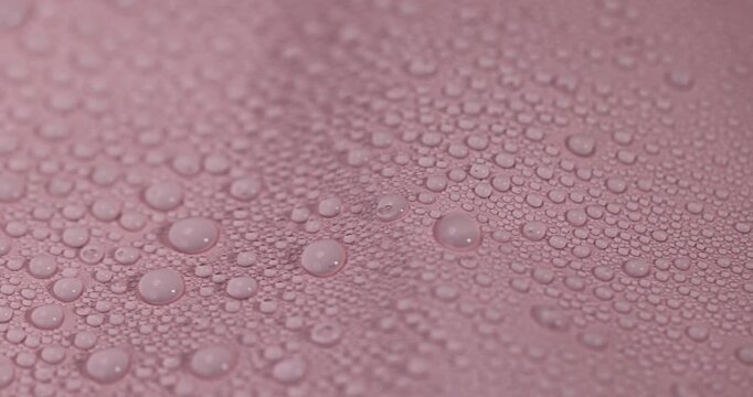 The surface is covered in water droplets, a pink waterproof surface with lots of small droplets and a wrinkled texture in even light with clear details and an organic look.