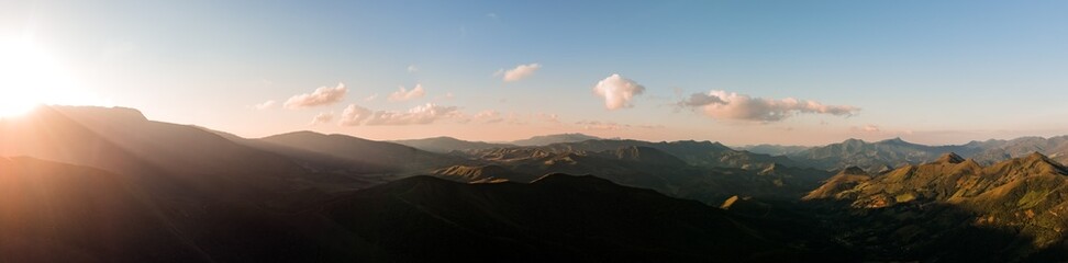 Obraz premium Fotografia aérea panorâmica da Serra da Mantiqueira, Minas Gerais, Brasil, com pôr do sol dourado iluminando montanhas, paisagem natural cinematográfica ideal para turismo, viagem e natureza.