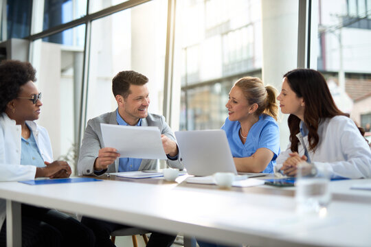 Happy mid adult businessman having a meeting with group of doctors in hospital