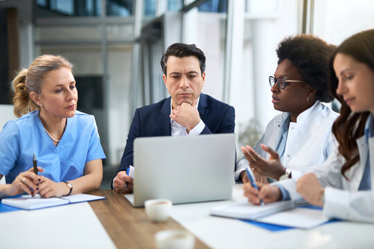 Mid adult businessman having a meeting with group of doctors in hospital