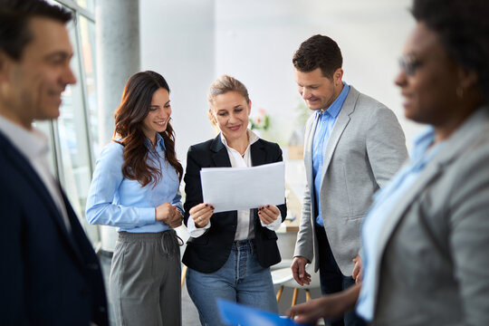 Happy business colleagues going through reports in a hallway of an office building