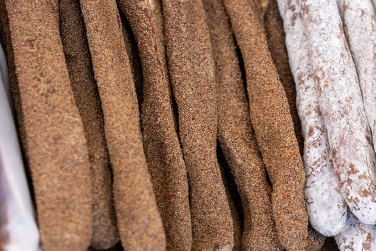 A top-down view of different types of cured fuet sausages, featuring pepper-crusted and white mold varieties.