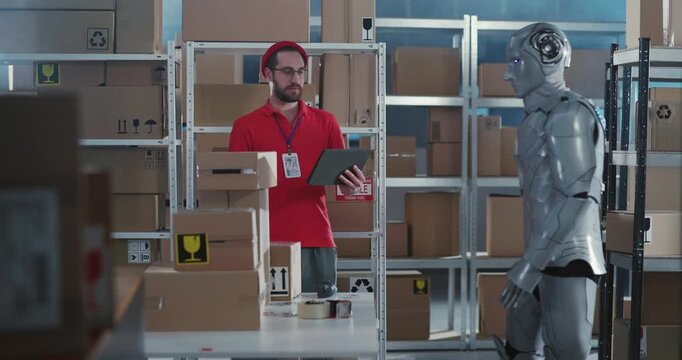 Humans and robots. Teamwork. Post office department workers cooperating in service workshop. Caucasian worker and robotic cyborg sorting delivery boxes together.