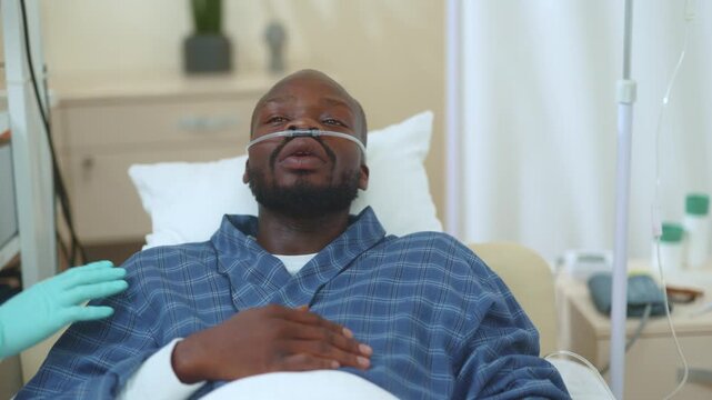 Poor sick african american young patient lying in bed hospital suffering high temperature flu symptoms wearing nasal cannula for normal breathing. Healthcare, disease concept.