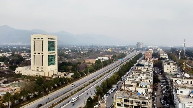 Aerial view of Islamabad city skyline with Jinnah Avenue and Margalla Hills under a hazy sky, Pakistan