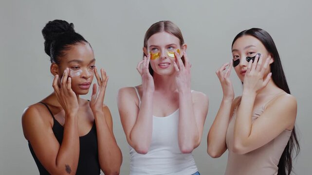 Multi-ethnic beautiful friendly girls wearing skincare cosmetic patches for dark circles healthy skin. Eye treatment. Cosmetics concept.