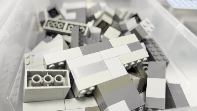 Gray and white building bricks in plastic storage bin
