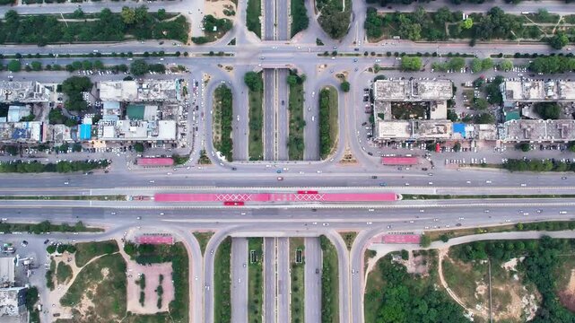Top Down Aerial View of a Modern City Road Interchange with Red Bus Stations and Green Urban Spaces