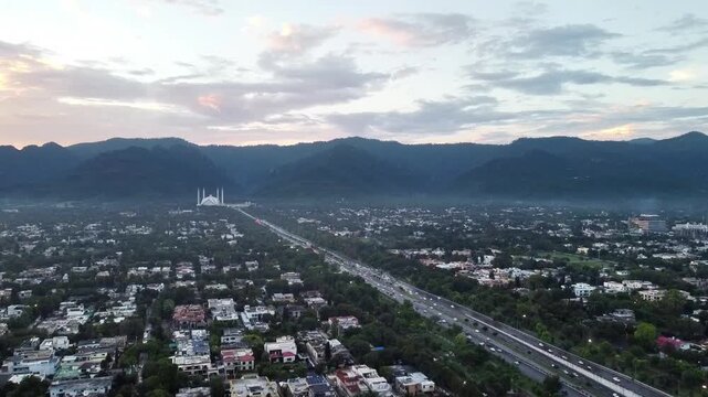 Wide Aerial View of Islamabad Cityscape and Faisal Mosque at the Base of Margalla Hills During Sunset