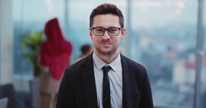 Face of handsome caucasian young man waiting for business trip in departure lounge smiling to camera. Multi-ethnic passengers in background.