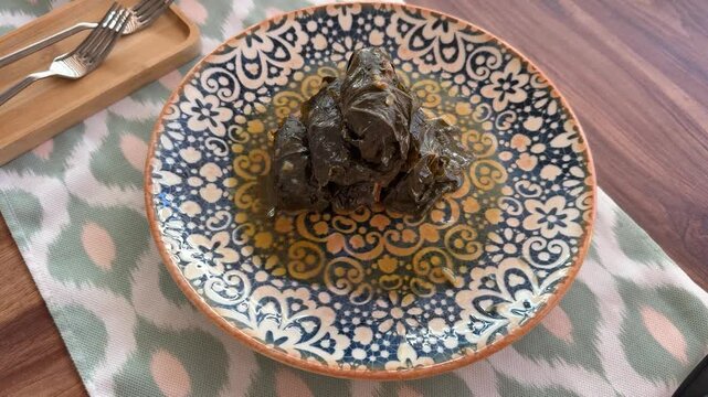 Turkish dolma served on an ornate plate with floral patterns on a wooden table background