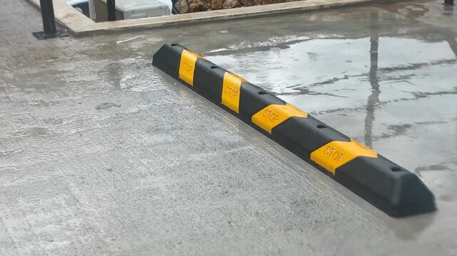 Speed bump on wet concrete parking lot surface, ideal as urban infrastructure background